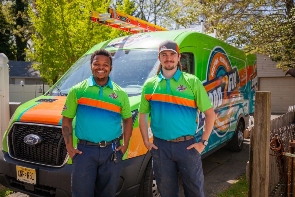 Two Good 2 Go technicians smiling in front of their service van